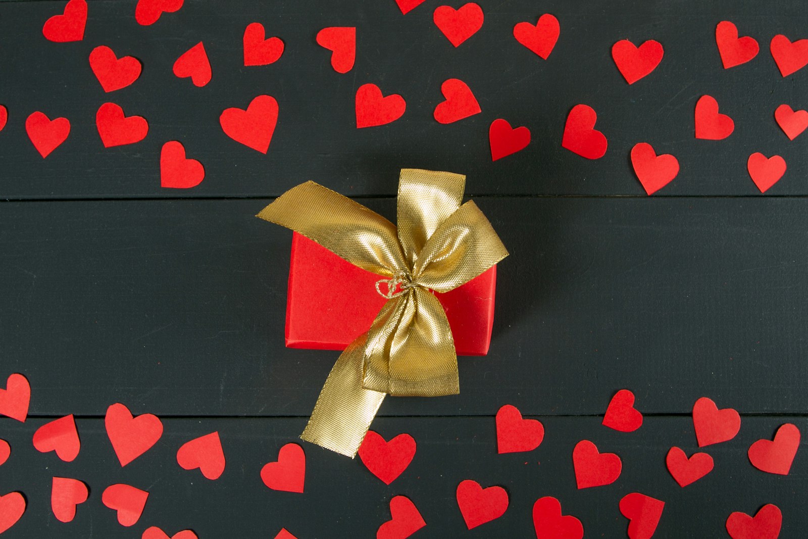 A red gift box with a gold ribbon and bow